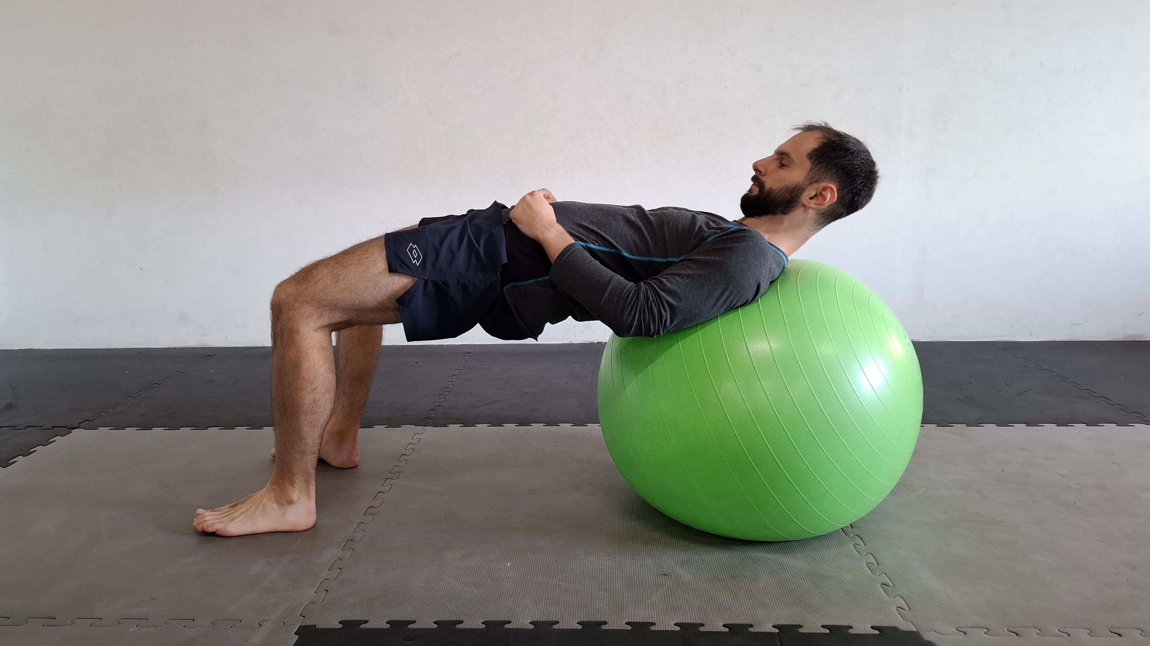 Muž cvičí na gymnastickém míči – zvedání pánve se zády na míči.